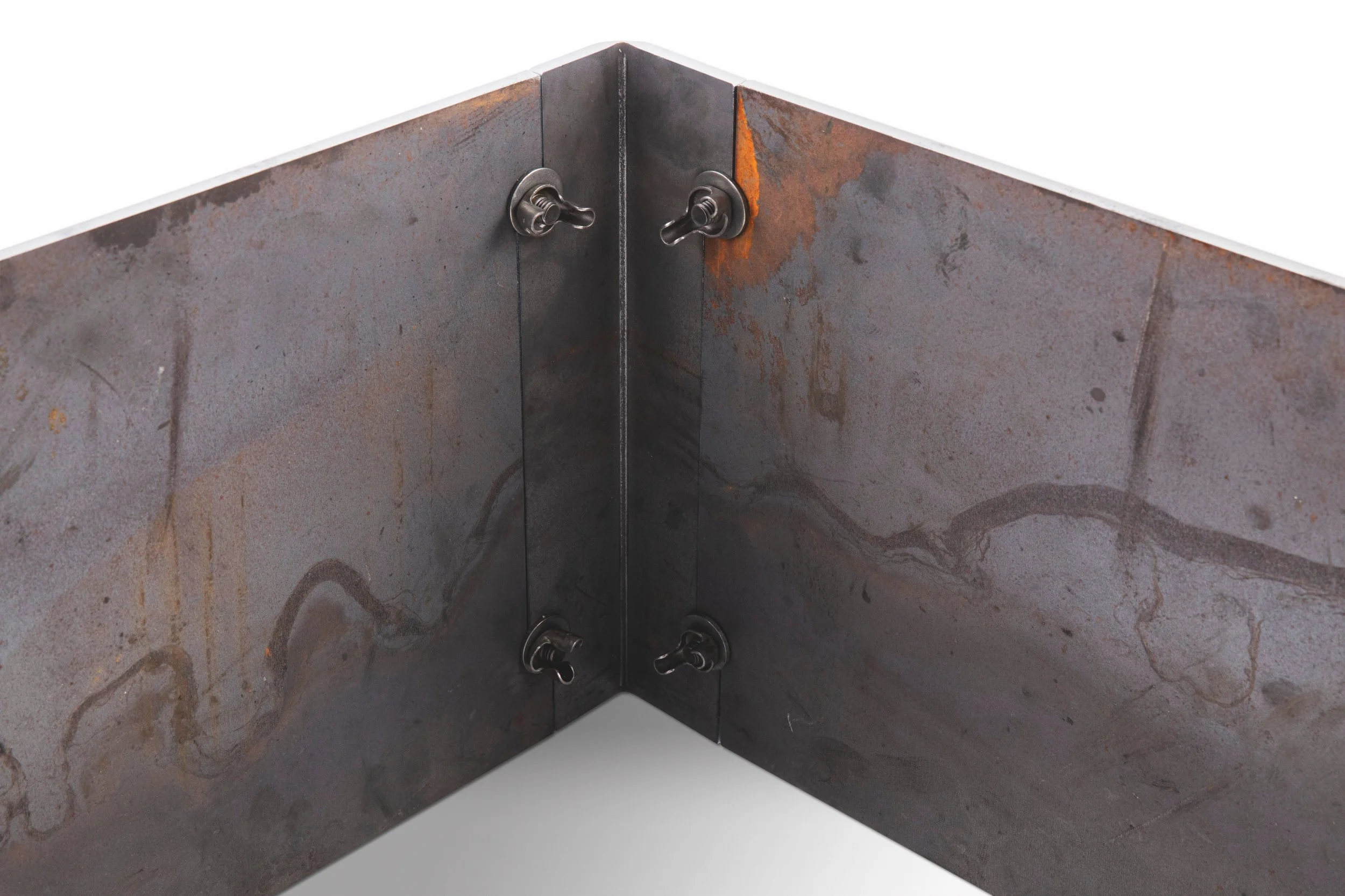 A corner of a metal sheet with rust spots, held together with four bolts, showing signs of oxidation.