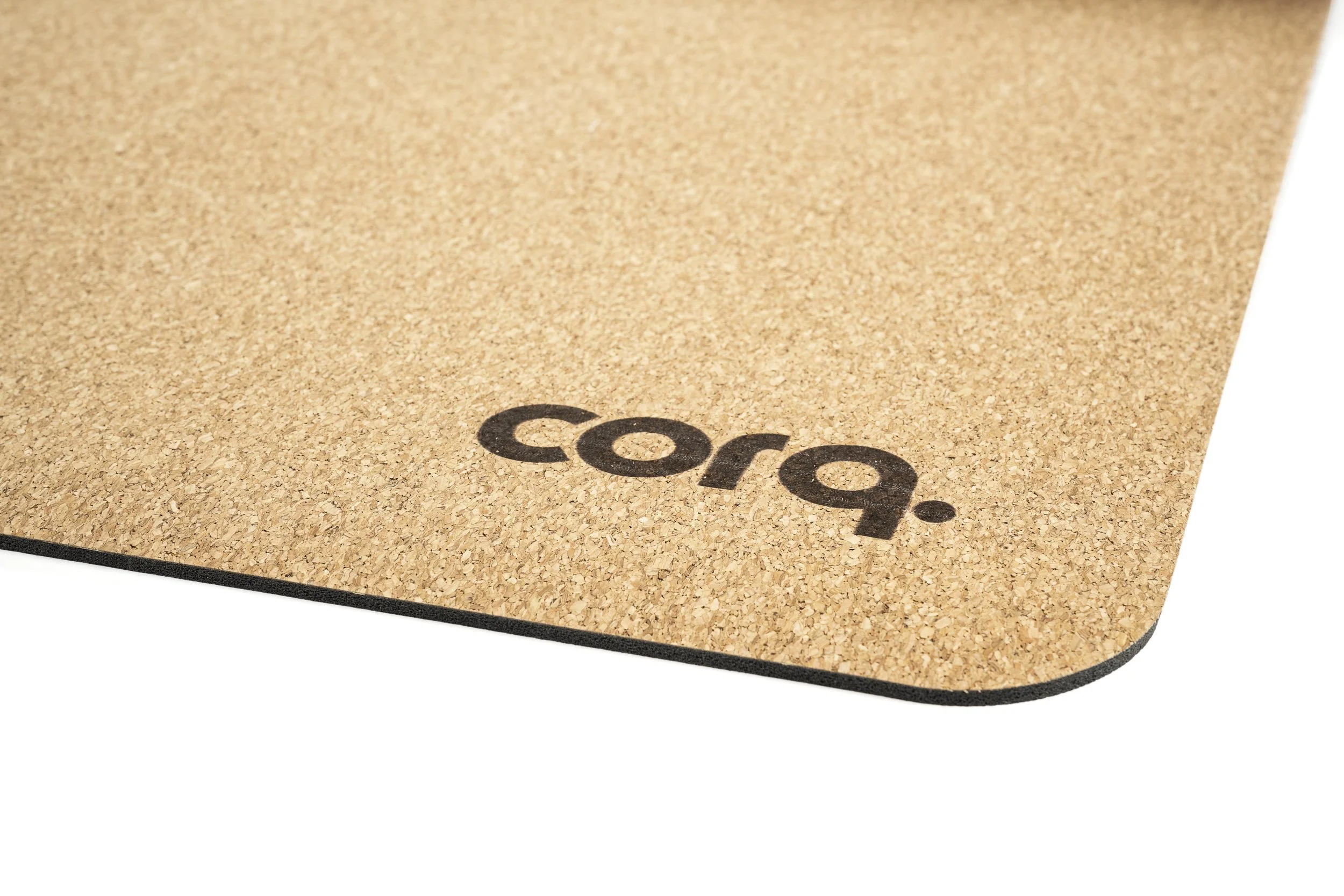 Close-up of a cork yoga mat with the brand name 'cora' printed on it.