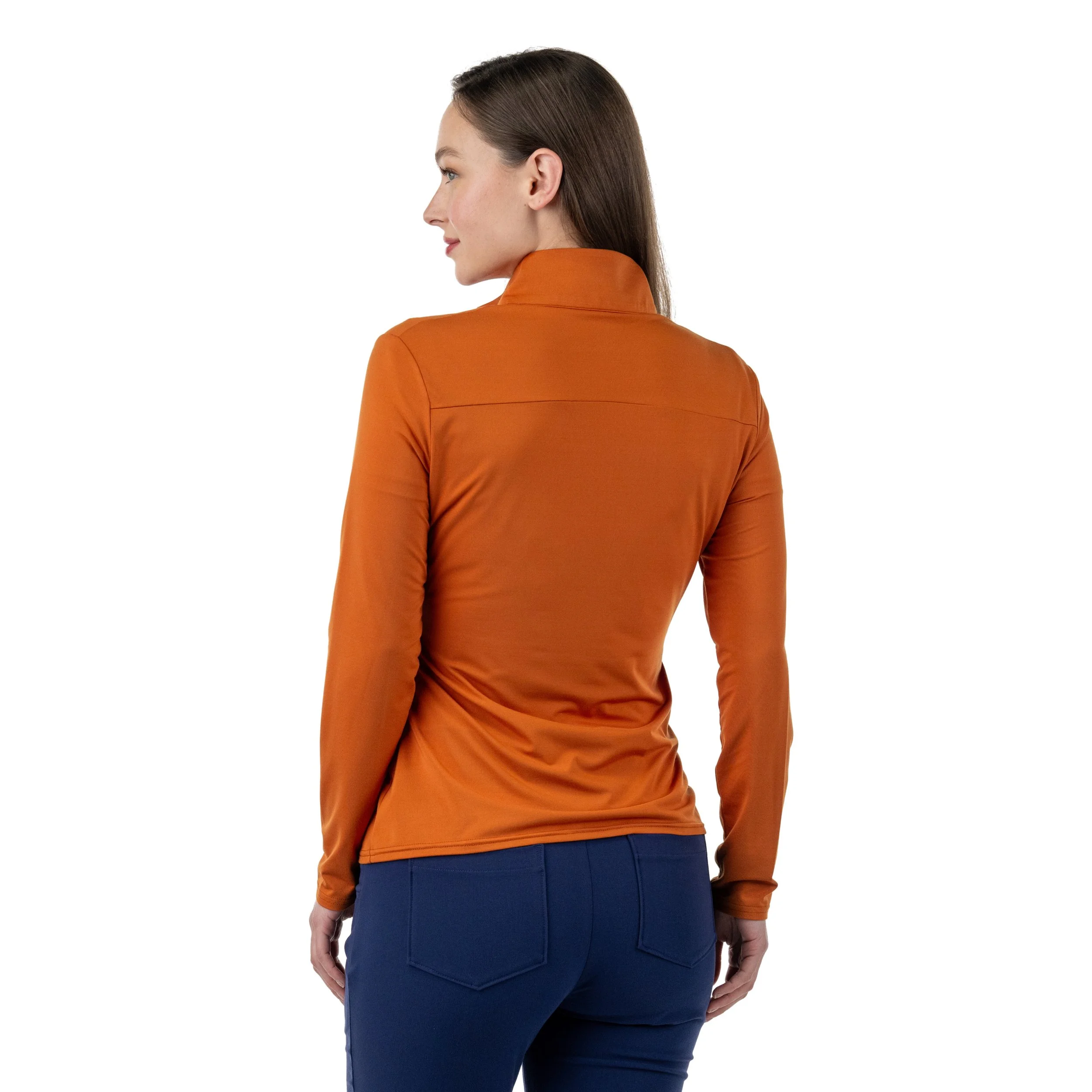 Back view of a woman wearing an orange jacket and blue pants, standing against a white background.