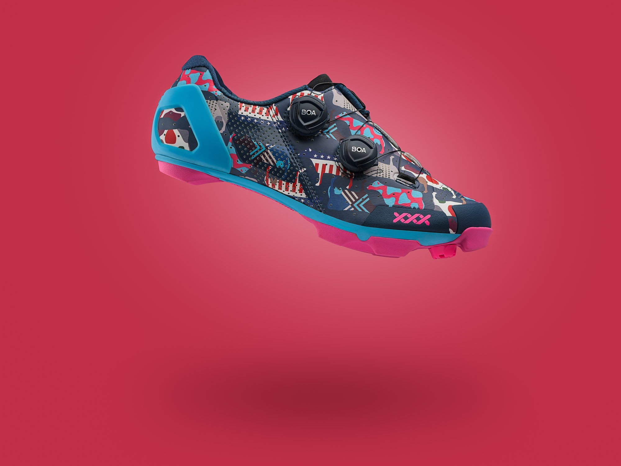 A colorful athletic shoe with a camouflage pattern, featuring black BOA closure dials, blue accents, and pink sole and branding, floating against a pink gradient background.