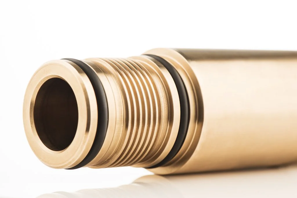 Close-up of a cylindrical metallic object with black rubber rings, possibly a firearm barrel or a mechanical component.