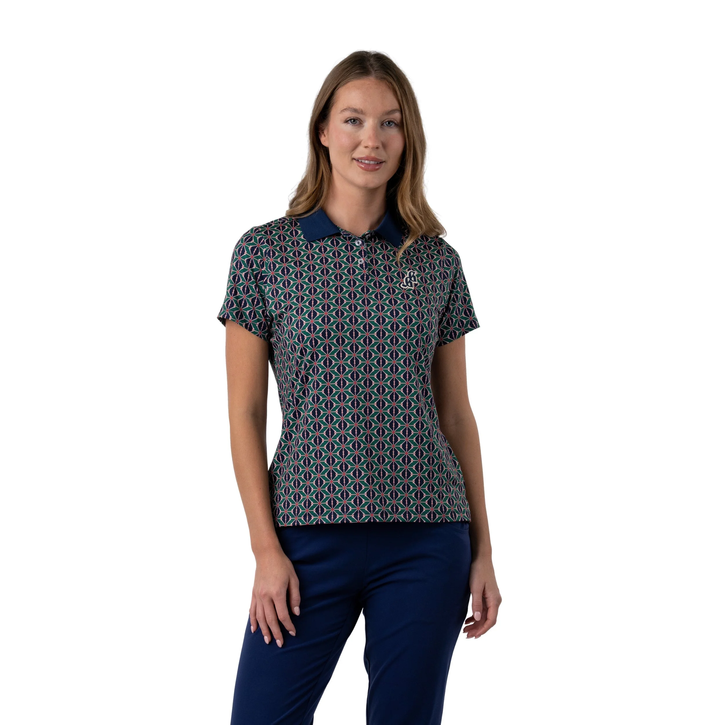 A woman with long blonde hair wearing a patterned golf shirt with a navy collar and navy pants, standing against a plain white background.