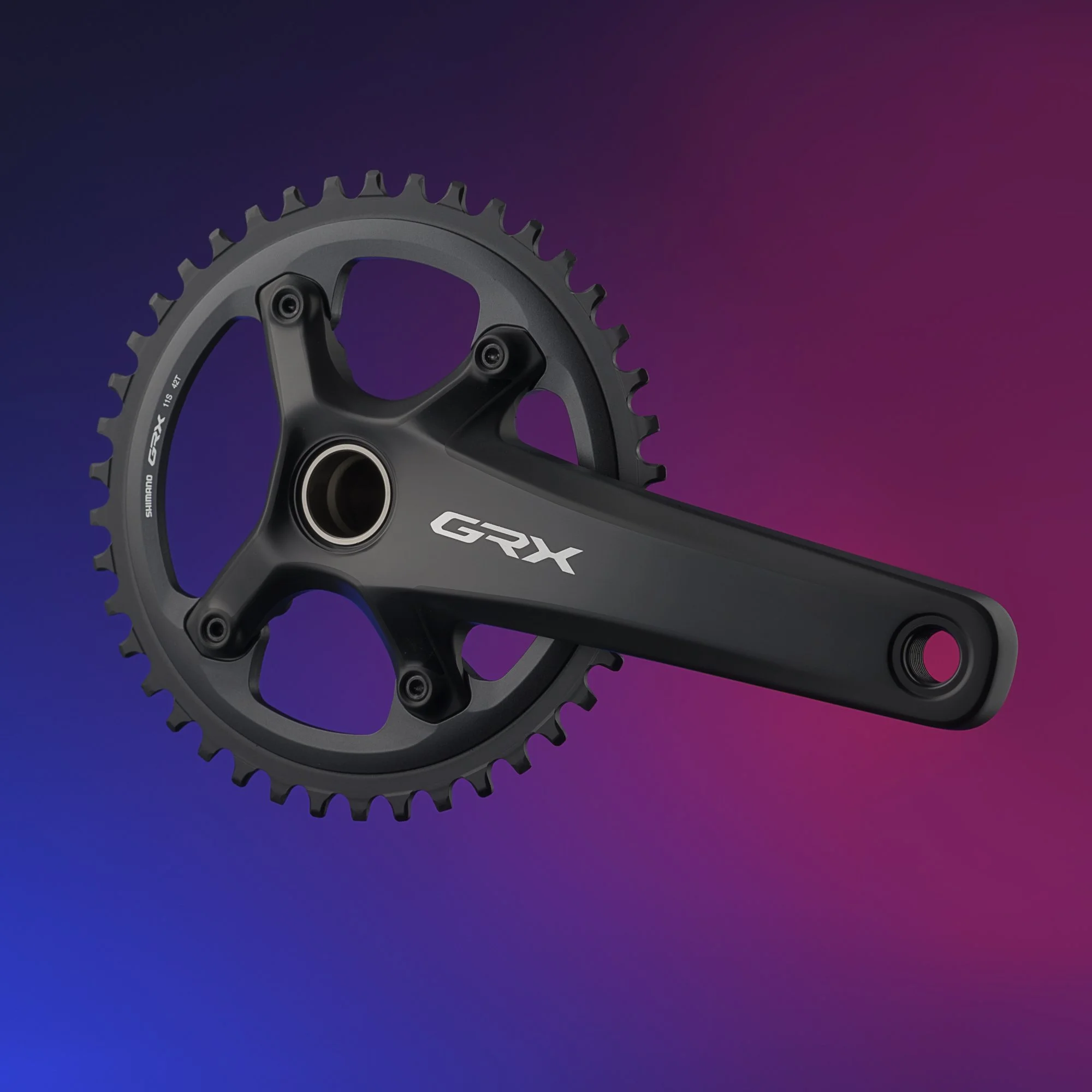 Bike crankset with chainring labeled GGX against a gradient background of blue and pink.