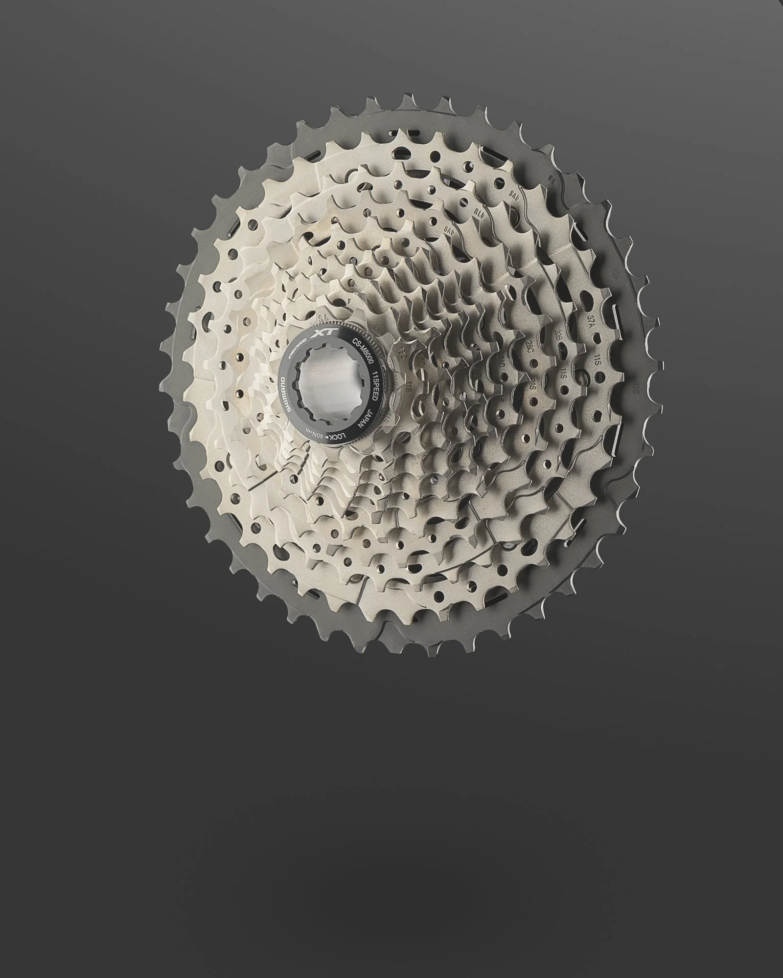 A bicycle gear cassette with multiple sprockets stacked together, viewed against a dark background.