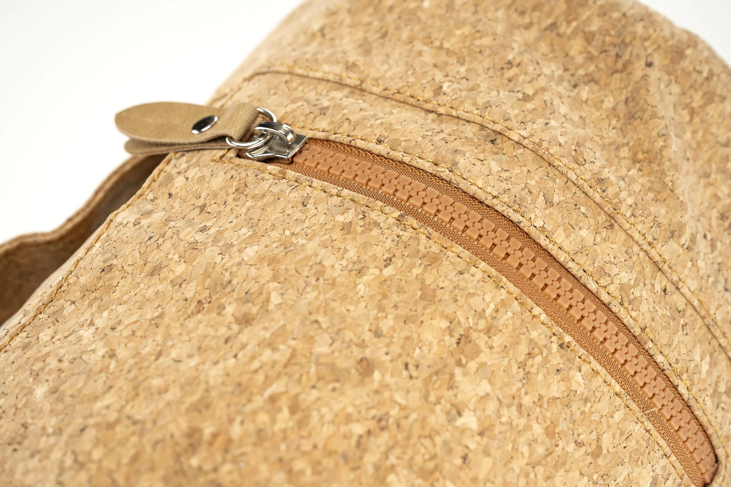 Close-up of a cork backpack with a tan zipper and a metal buckle.