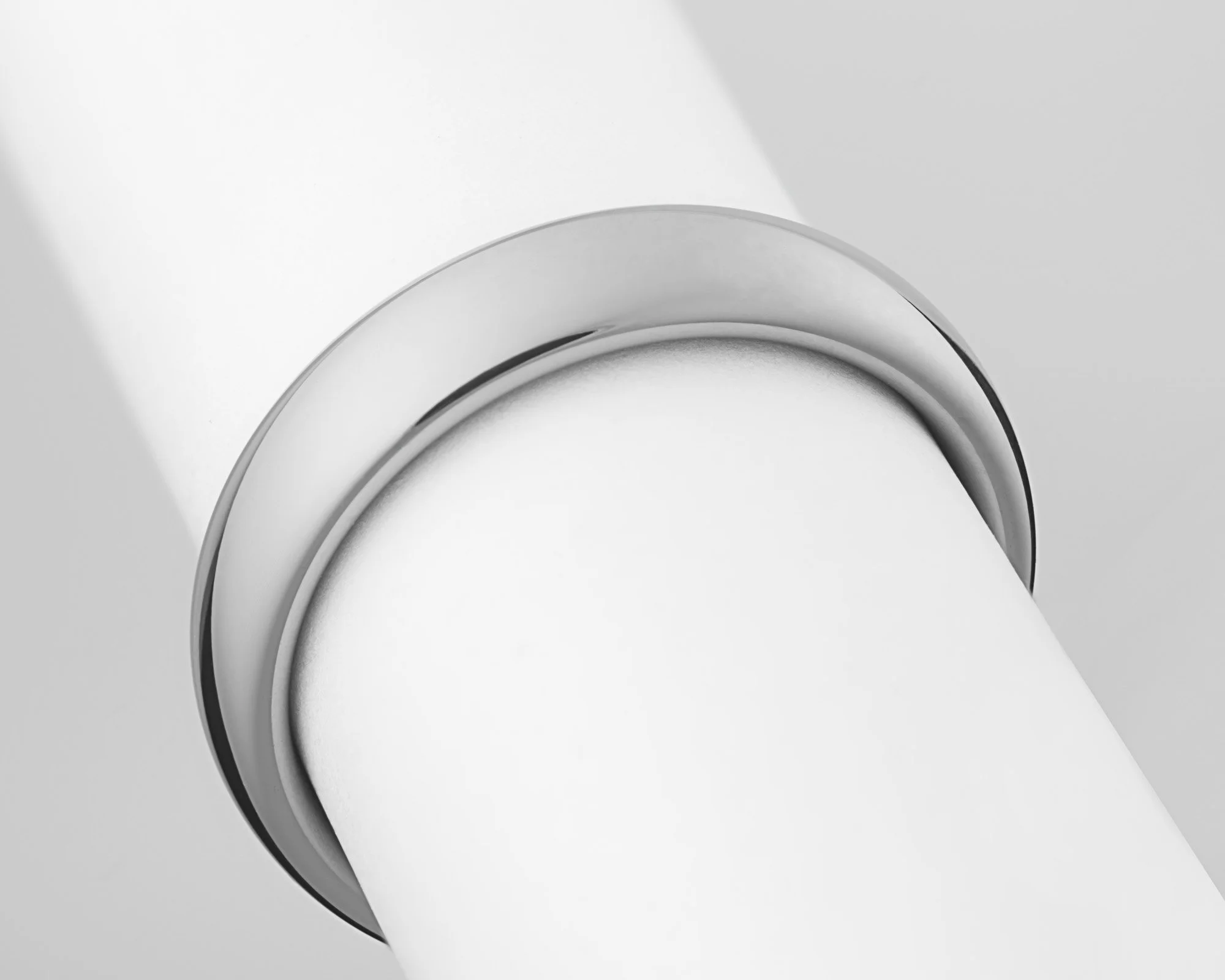 Close-up of a white cylindrical object with a silver ring near the top, viewed from below.