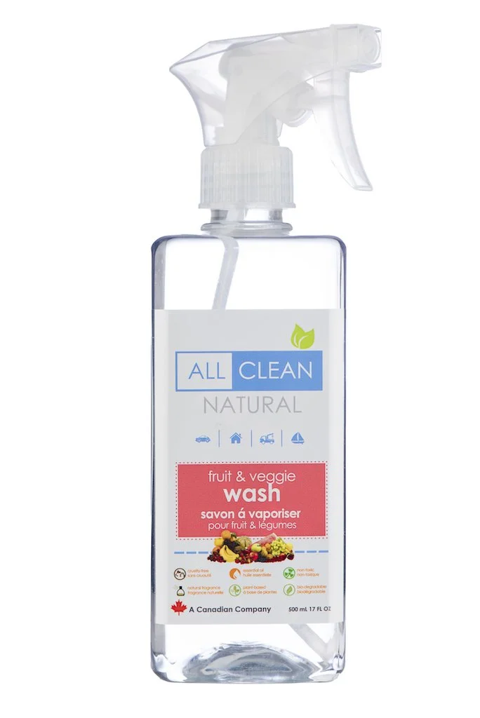 A clear spray bottle labeled 'All Clean Natural' with a green leaf icon and a pink label that reads 'fruit & veggie wash' with a picture of various fruits and vegetables.