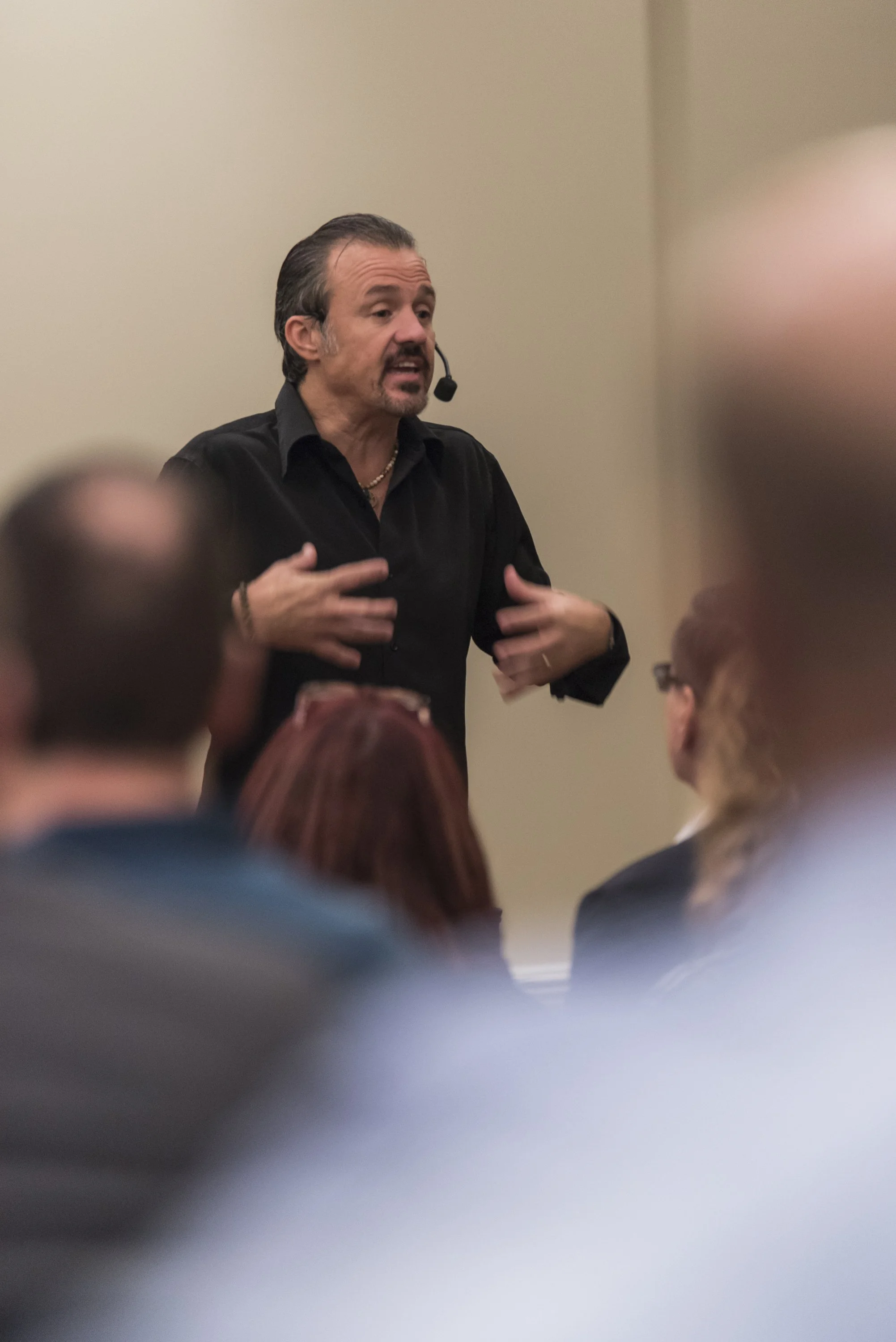 A man with a microphone headset giving a presentation to an audience.