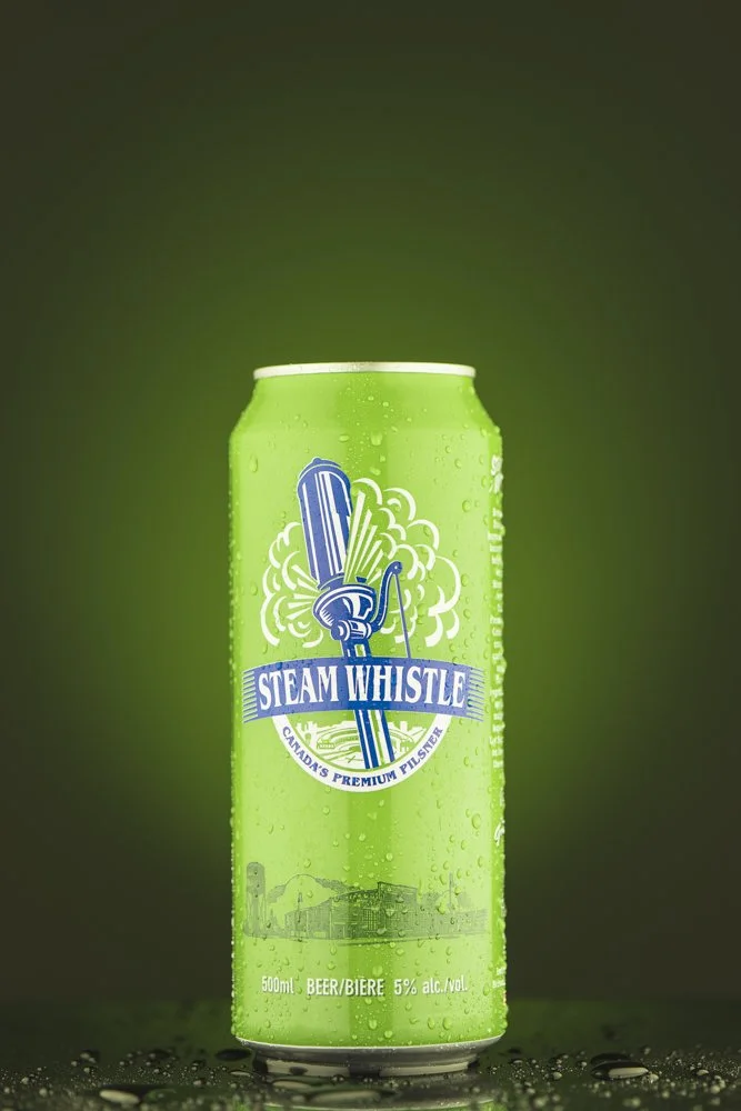Green can of Steam Whistle beer with condensation droplets, featuring a vintage steam whistle logo with steam, and the text "Canada's Premium Pilsner" and "500 ml, 5% alcohol".
