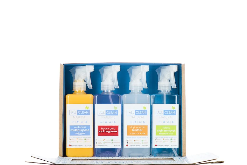 Four spray bottles of cleaning solutions in a cardboard box, labeled for multi-purpose, heavy-duty spot degreaser, vinyl, wood and leather, and fabric stain remover.