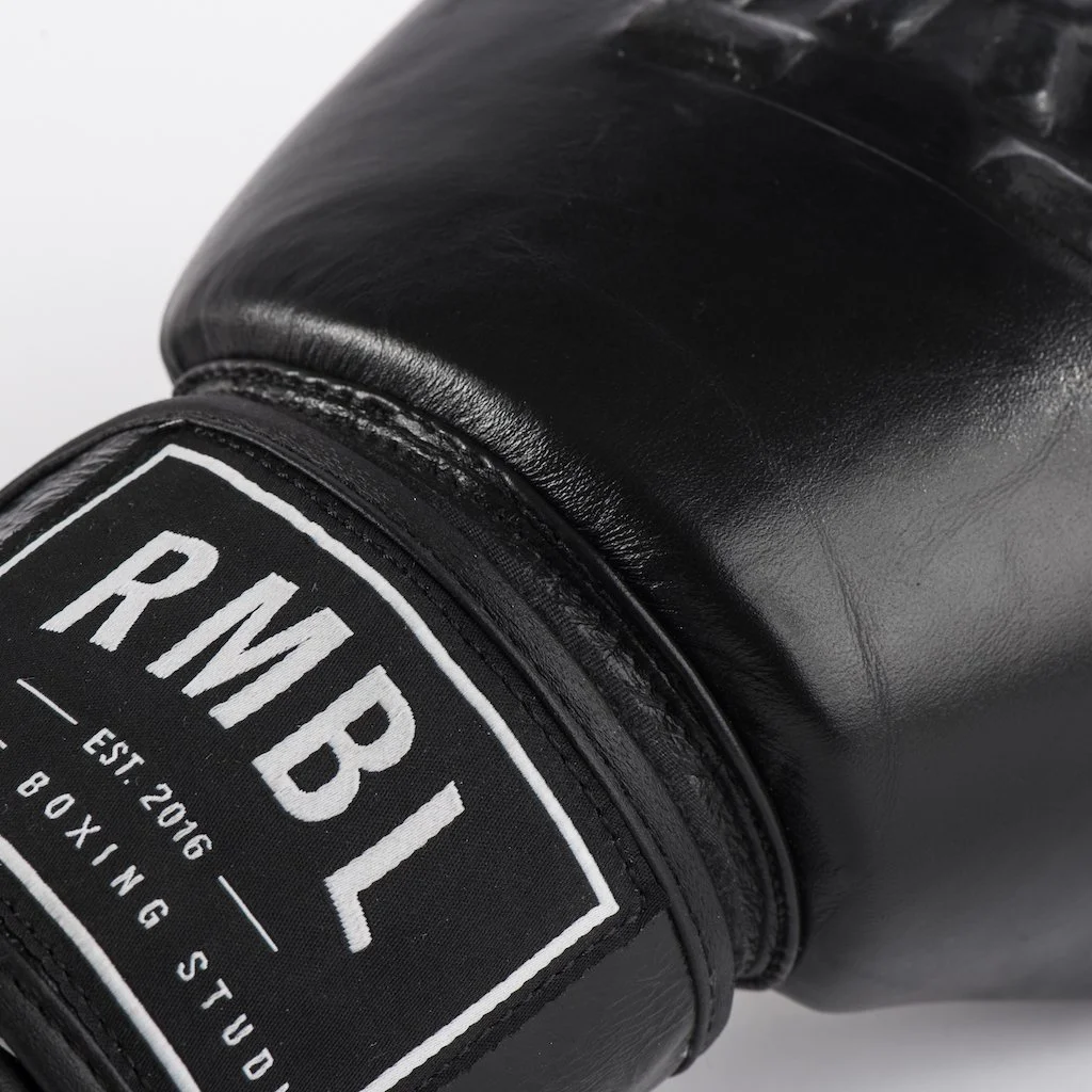 Close-up of a black boxing glove with a label that says 'RMBL' and 'Established 2016 Boxing Studio'.