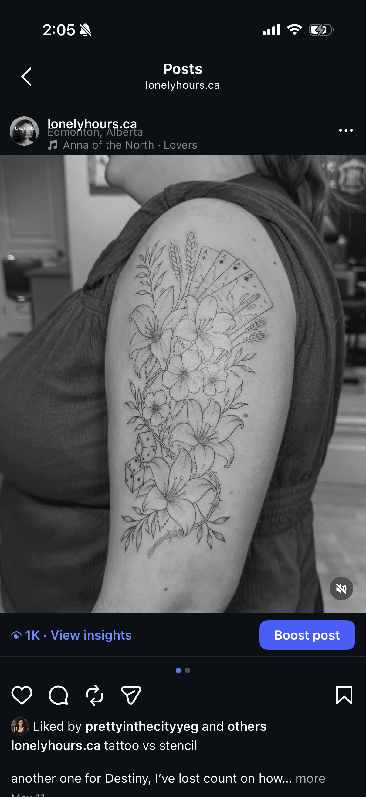 Black and white photo of a woman's upper arm with a tattoo featuring flowers, leaves, dice, and playing cards.