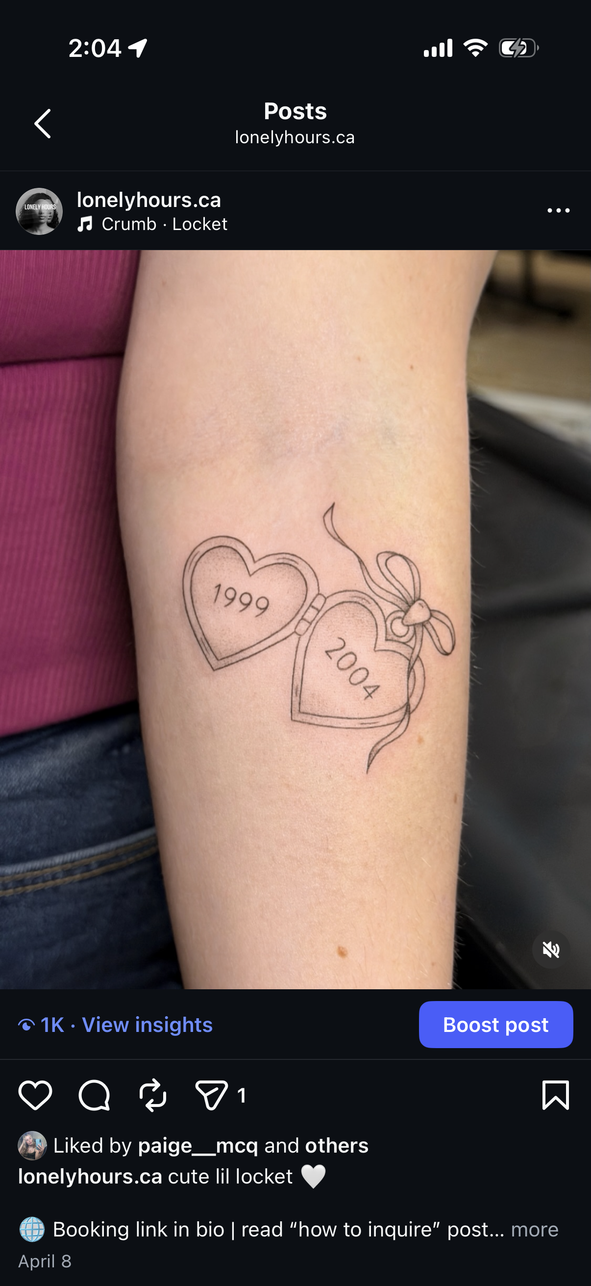 Tattoo of two heart-shaped lockets with the years 1999 and 2004 inside, tied together with a ribbon, on a person's forearm.