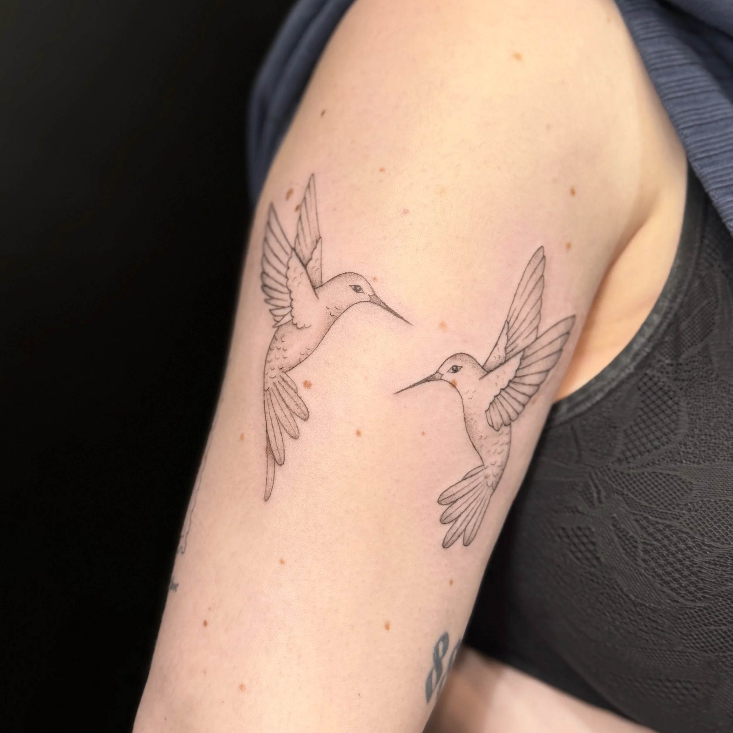 Close-up of a person's arm with a tattoo of a bird in flight, and small freckles on the skin.