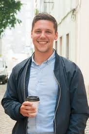 Smiling man holding coffee cup outdoors in an urban setting