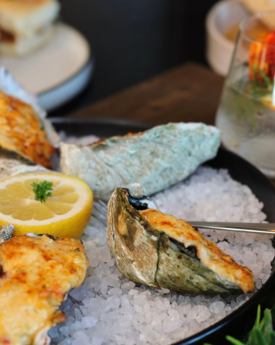 Close-up of our baked oysters on a bed of salt with lemon slices