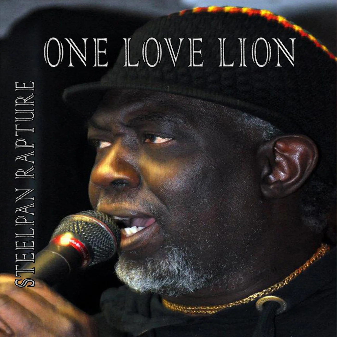 Een man met een zwart hoedje en goudkleurige kettingen, die zingt of spreekt in een microfoon.