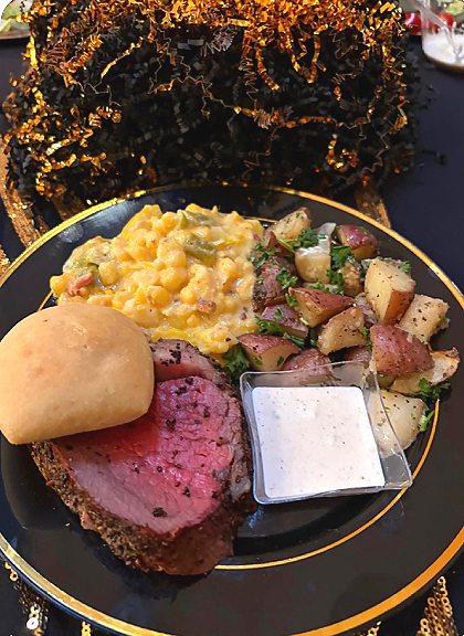 Catered birthday dinner with beef tenderloin, hominy casserole, roasted potatoes, and a roll