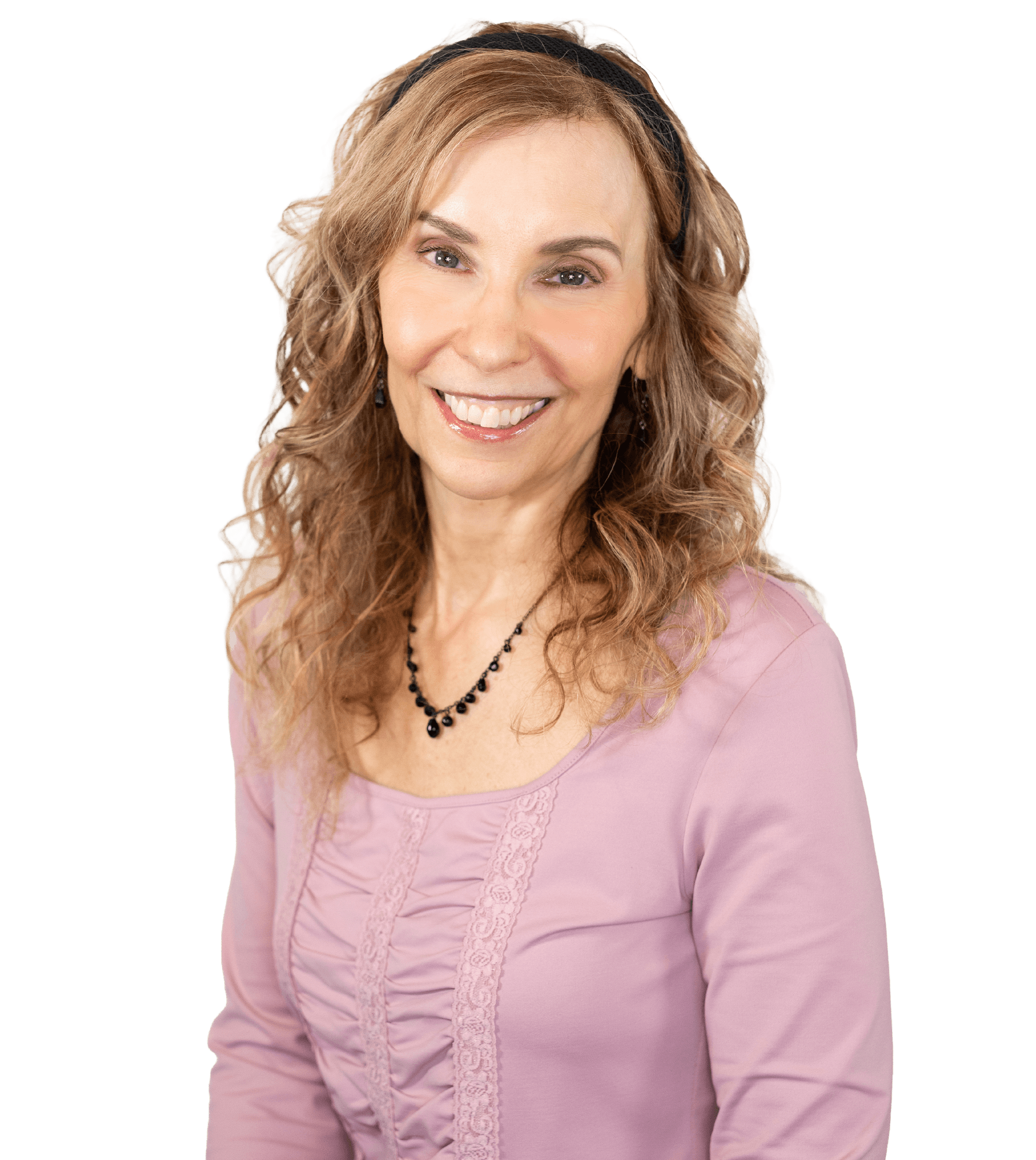 A smiling middle-aged woman with curly, light-brown hair wearing a pink top and a black beaded necklace.