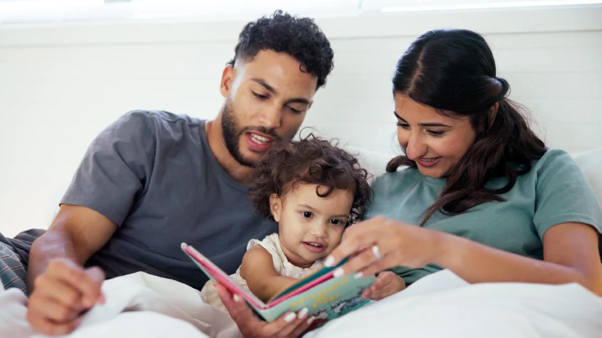Parents reading a book with their young child while sharing a warm moment that supports connection, communication, and early language development