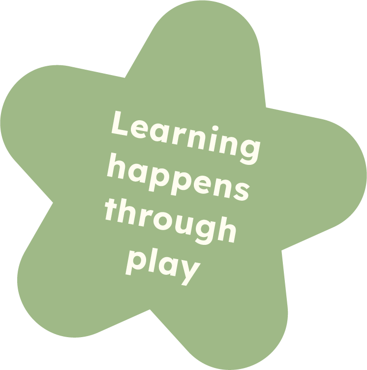 Green star-shaped sign with white text that says, "Learning happens through play."