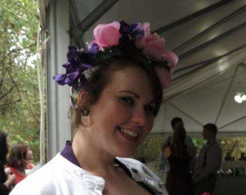 Smiling woman wearing a colorful purple and pink floral headpiece at an indoor event