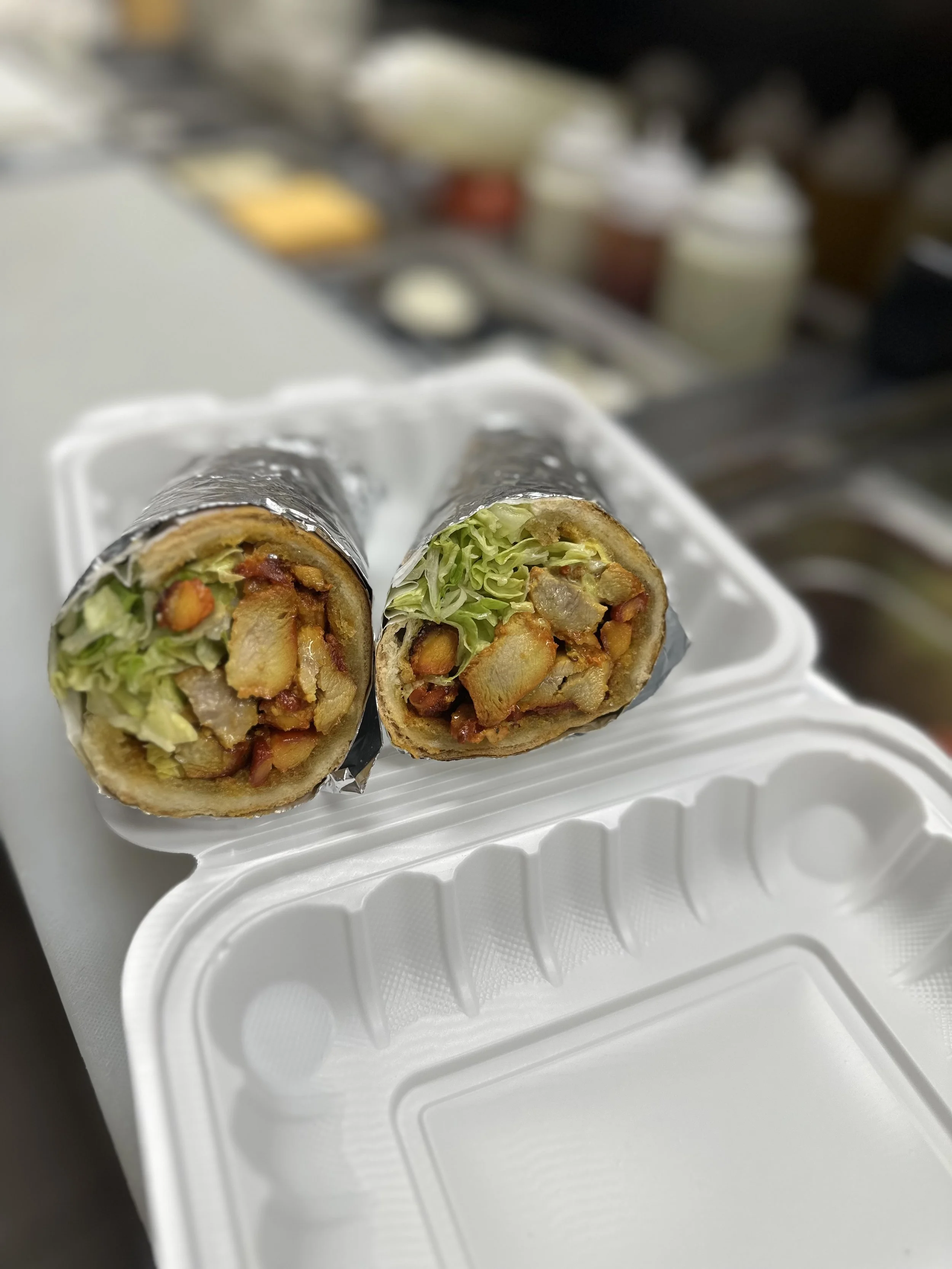 Close-up of a chopped open burrito with lettuce and seasoned meat, resting on a white takeout container.