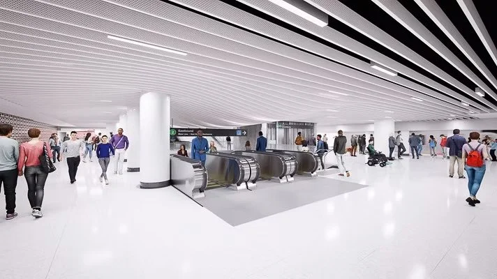 People walking and waiting in an airport terminal near escalators.