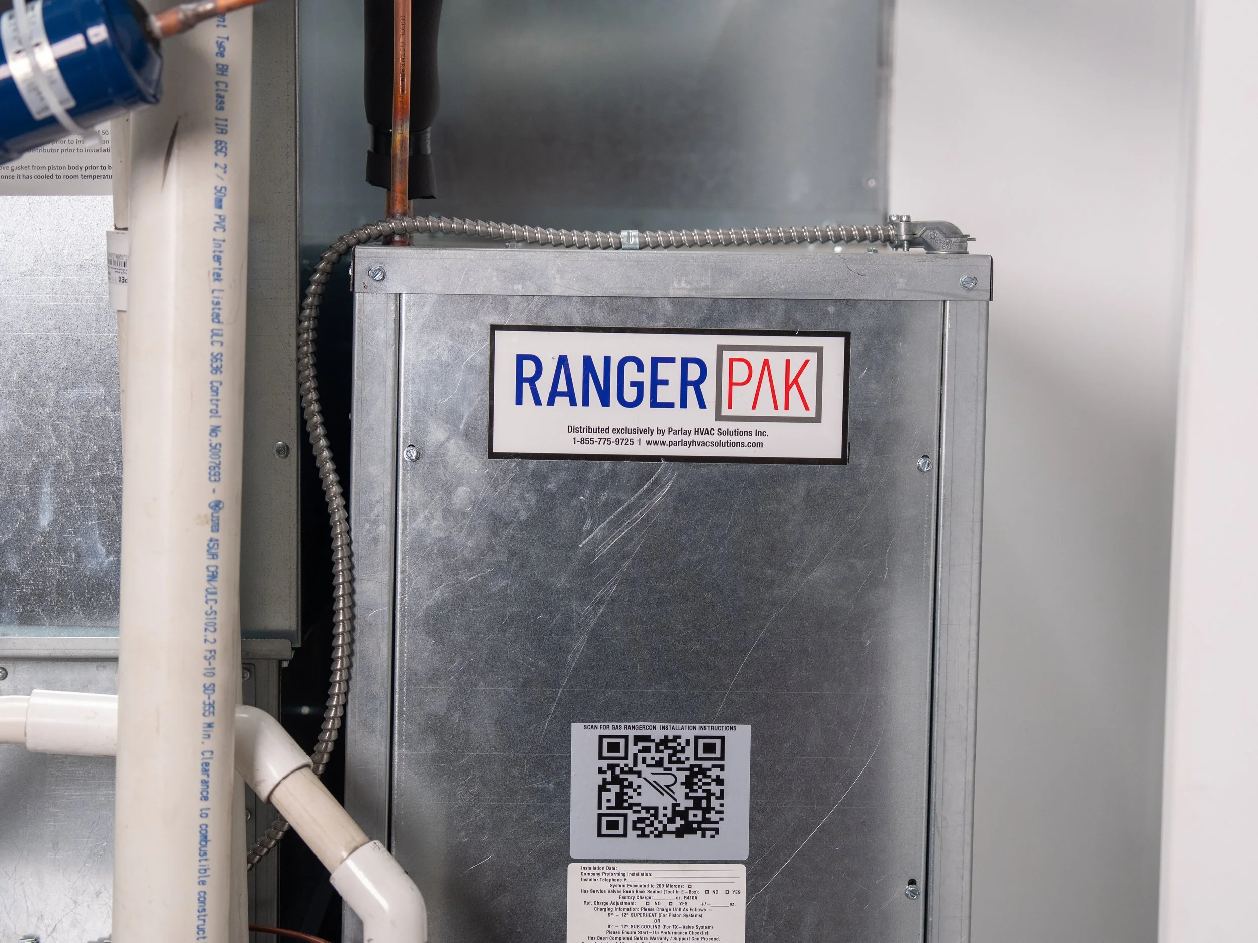 An industrial HVAC or ventilation control panel labeled 'R-SKYPAK,' with pipes and wiring surrounding it, in a utility or mechanical room.