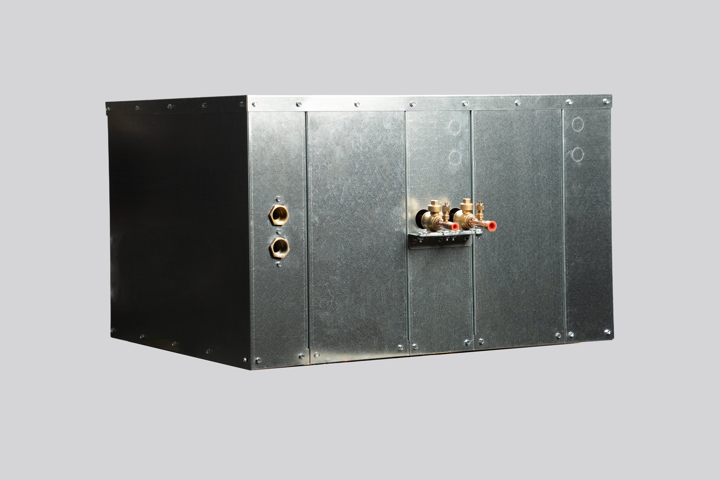 A metallic HVAC unit with brass pipe fittings and two black outlet ports on a plain gray background.