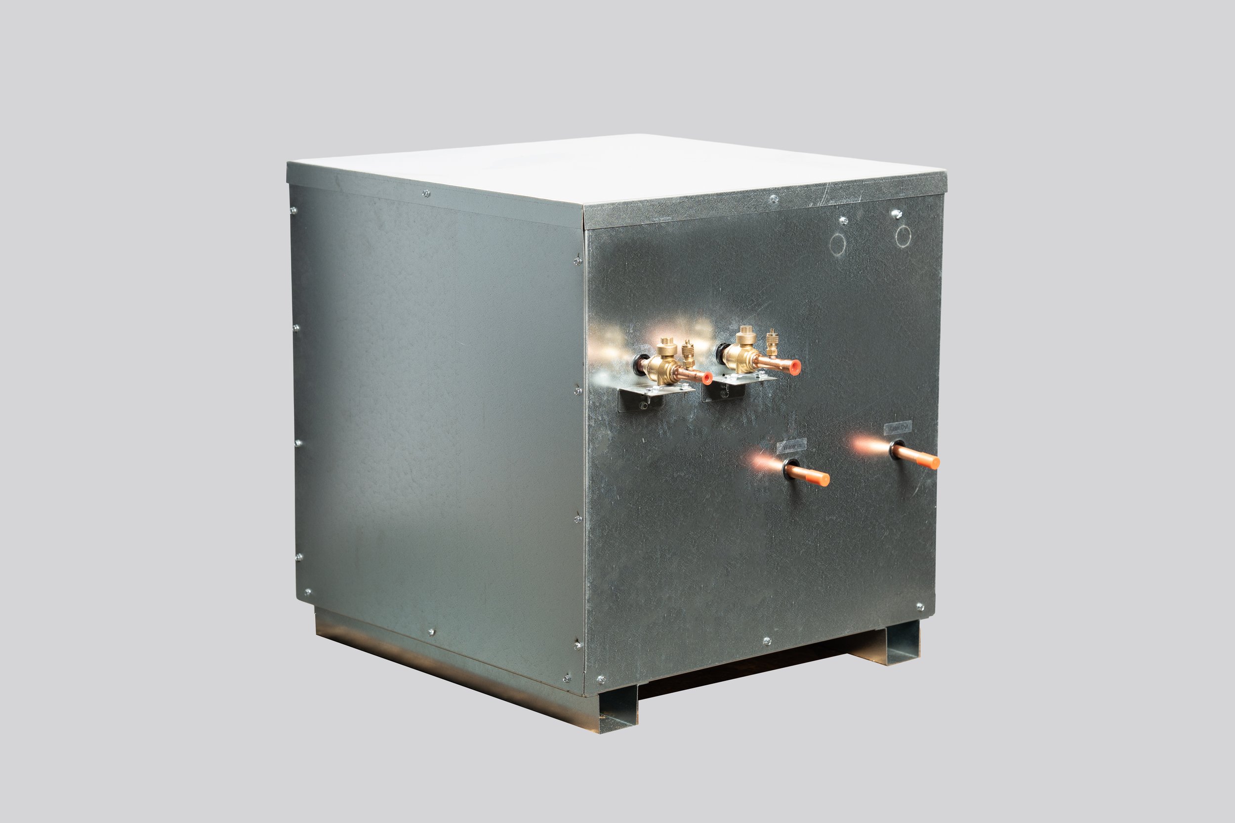 A metal industrial machine with brass valves and copper pipes, set against a plain gray background.