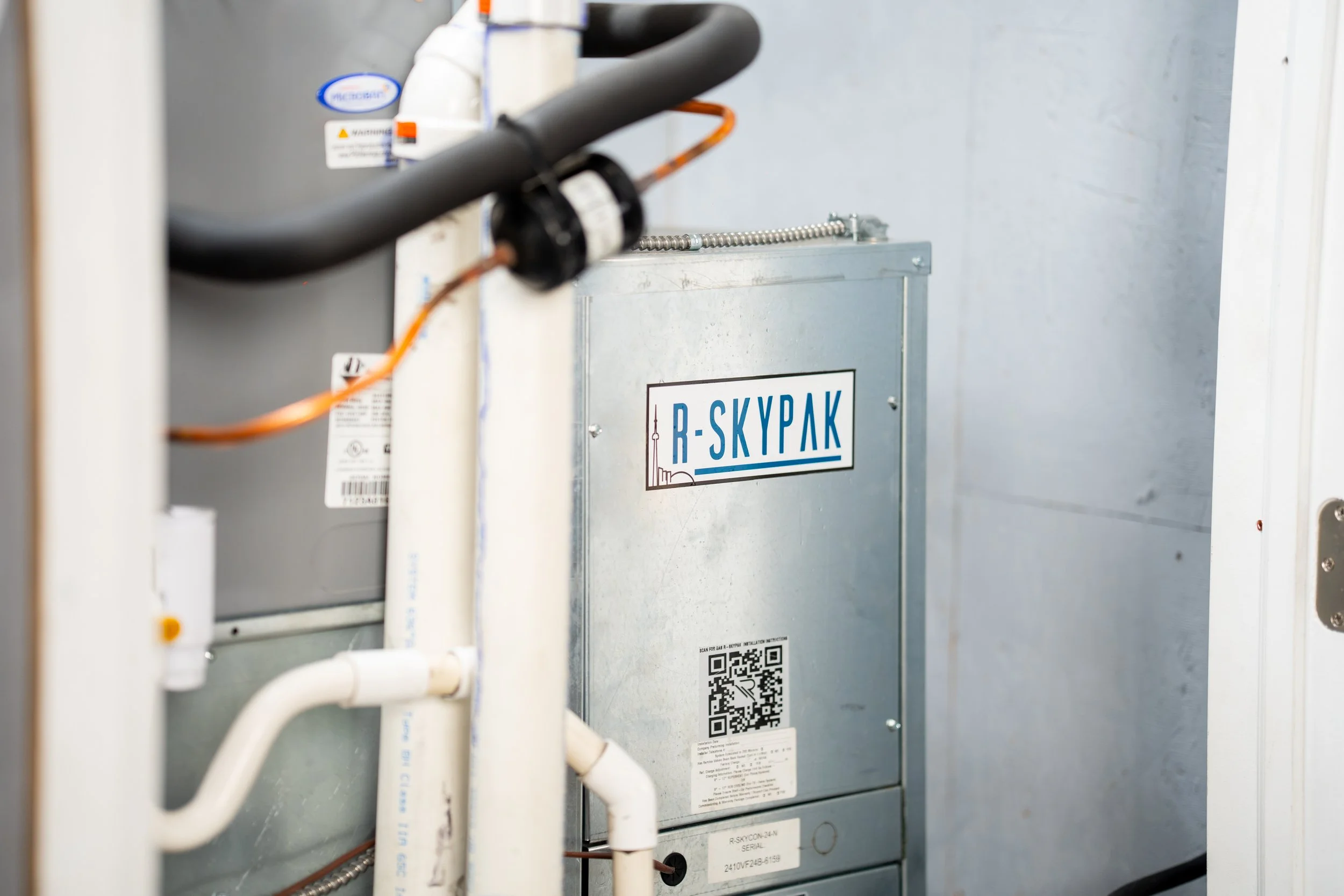 An industrial HVAC or ventilation control panel labeled 'R-SKYPAK,' with pipes and wiring surrounding it, in a utility or mechanical room.