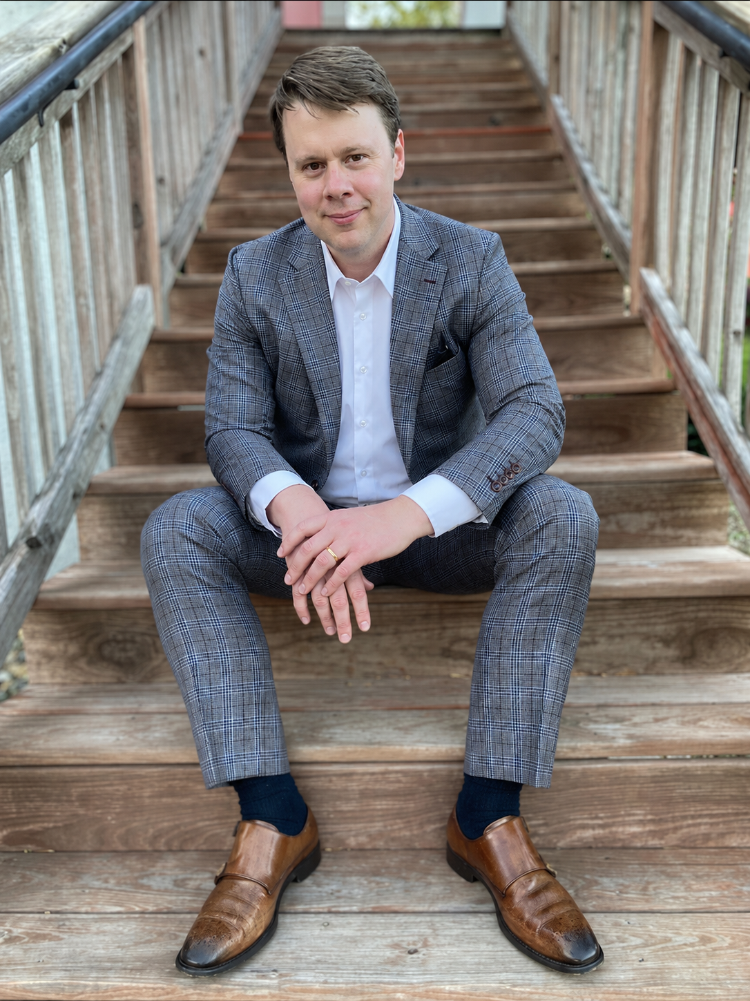 Steve Borchardt wearing a checkered suit and sitting on wooden outdoor stairs