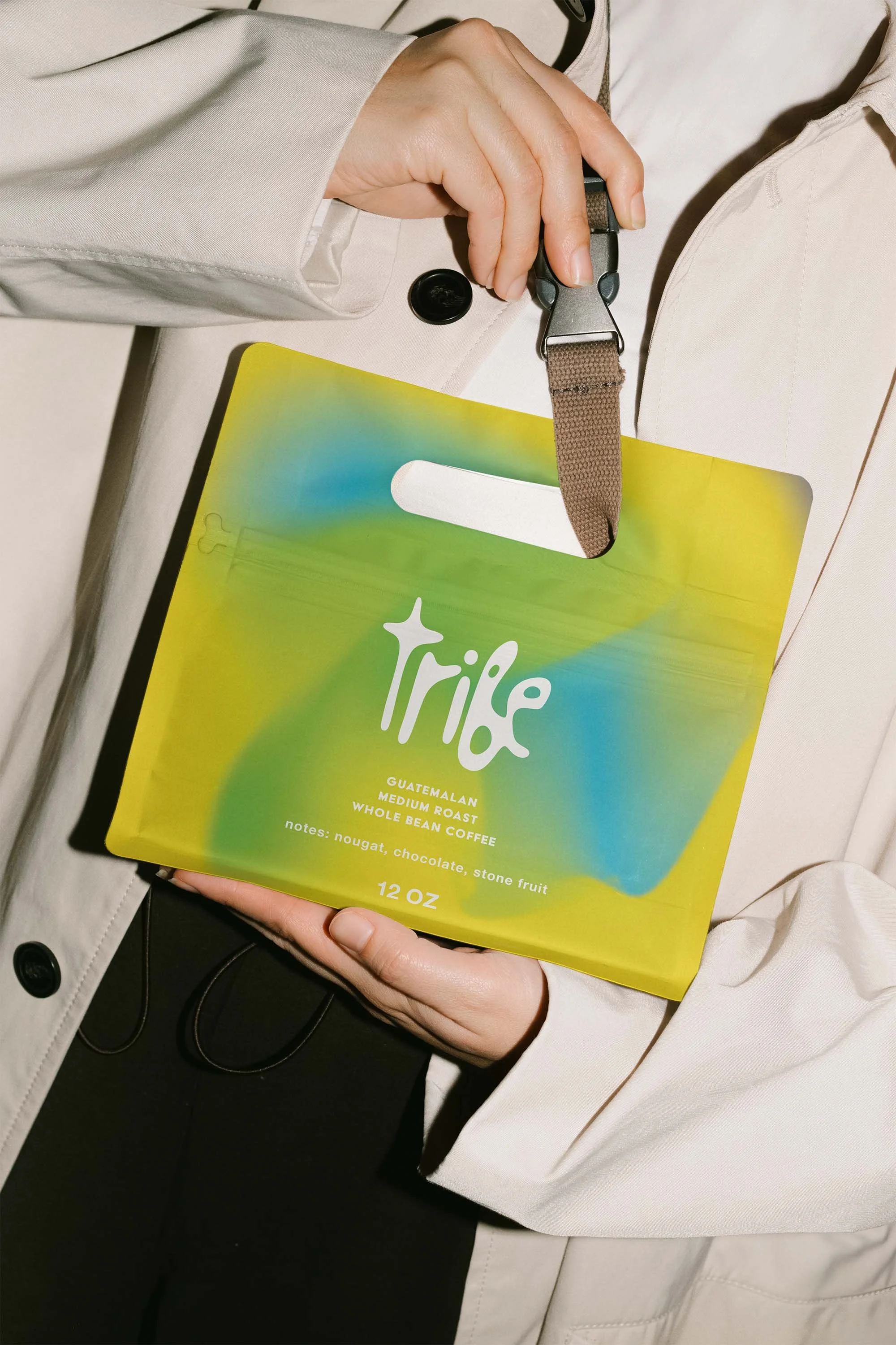 Person holding a bright, colorful package of Tribe Guatemala medium roast whole bean coffee with notes of nougat, chocolate, and stone fruit.