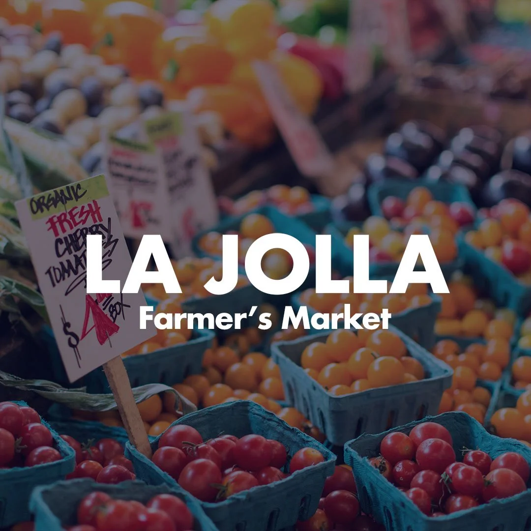 Colorful baskets of fresh tomatoes at a farmer's market with signs displaying prices.