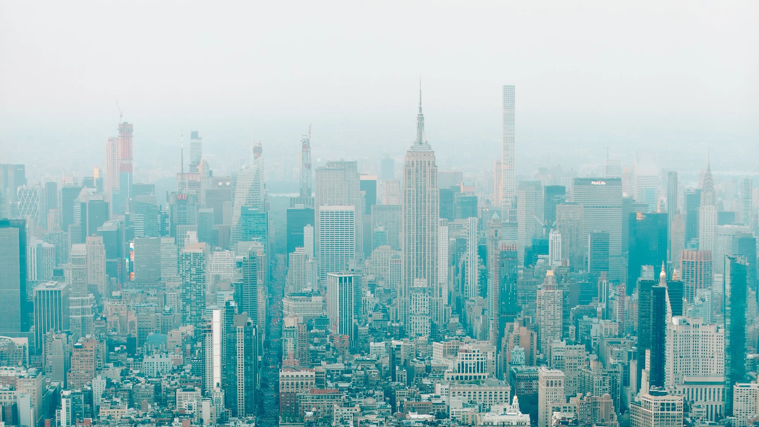 A panoramic view of the Manhattan skyline in New York City with numerous skyscrapers, including the Empire State Building.