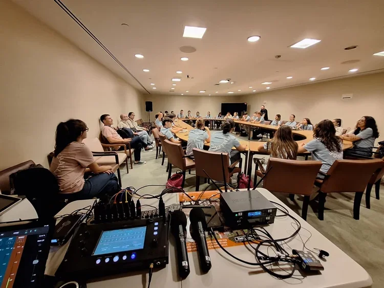 A large group of people sitting around a u-shaped conference table attending a meeting at United Nations.