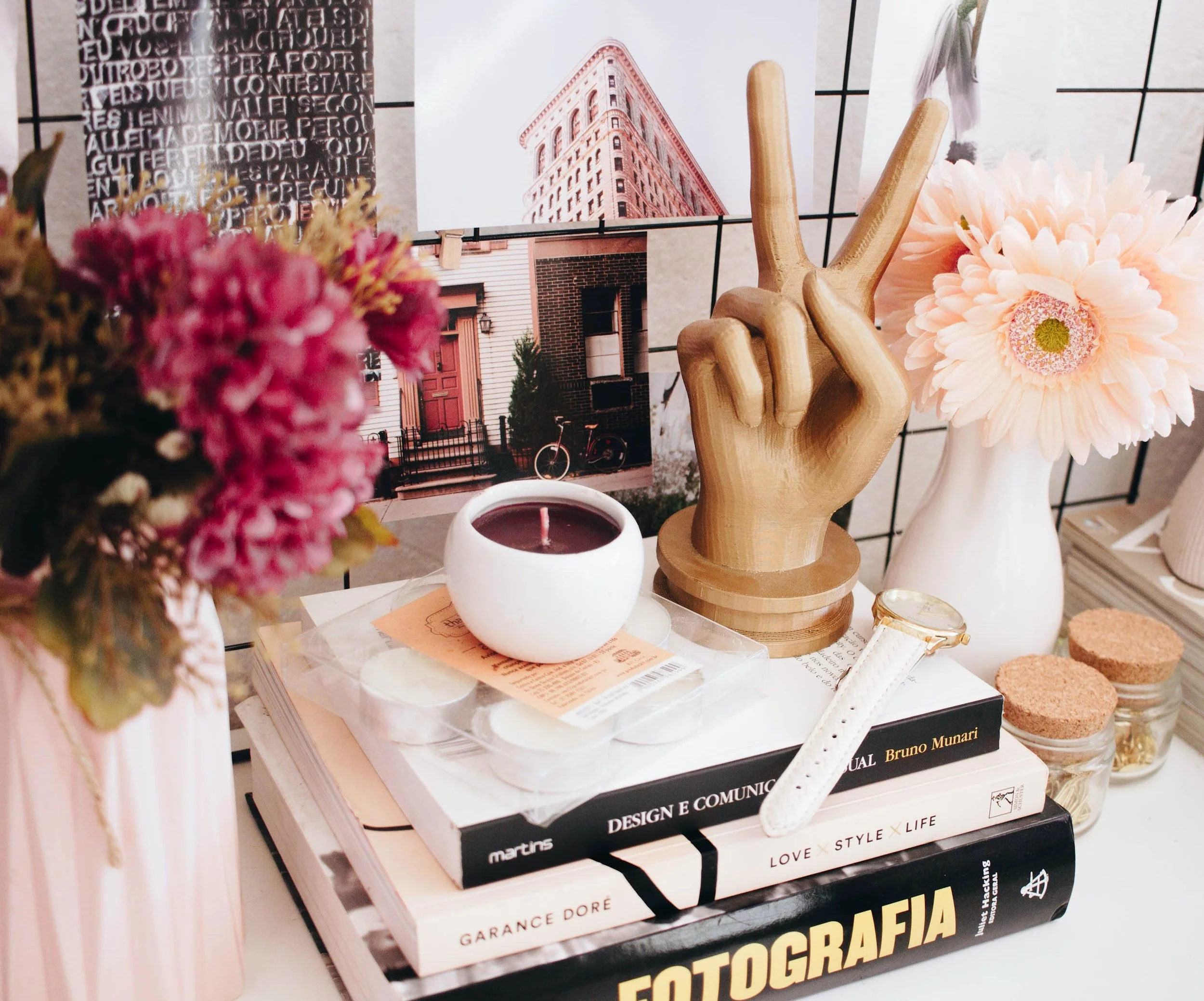 Books stacked with a wooden peace sign, flowers, and candles