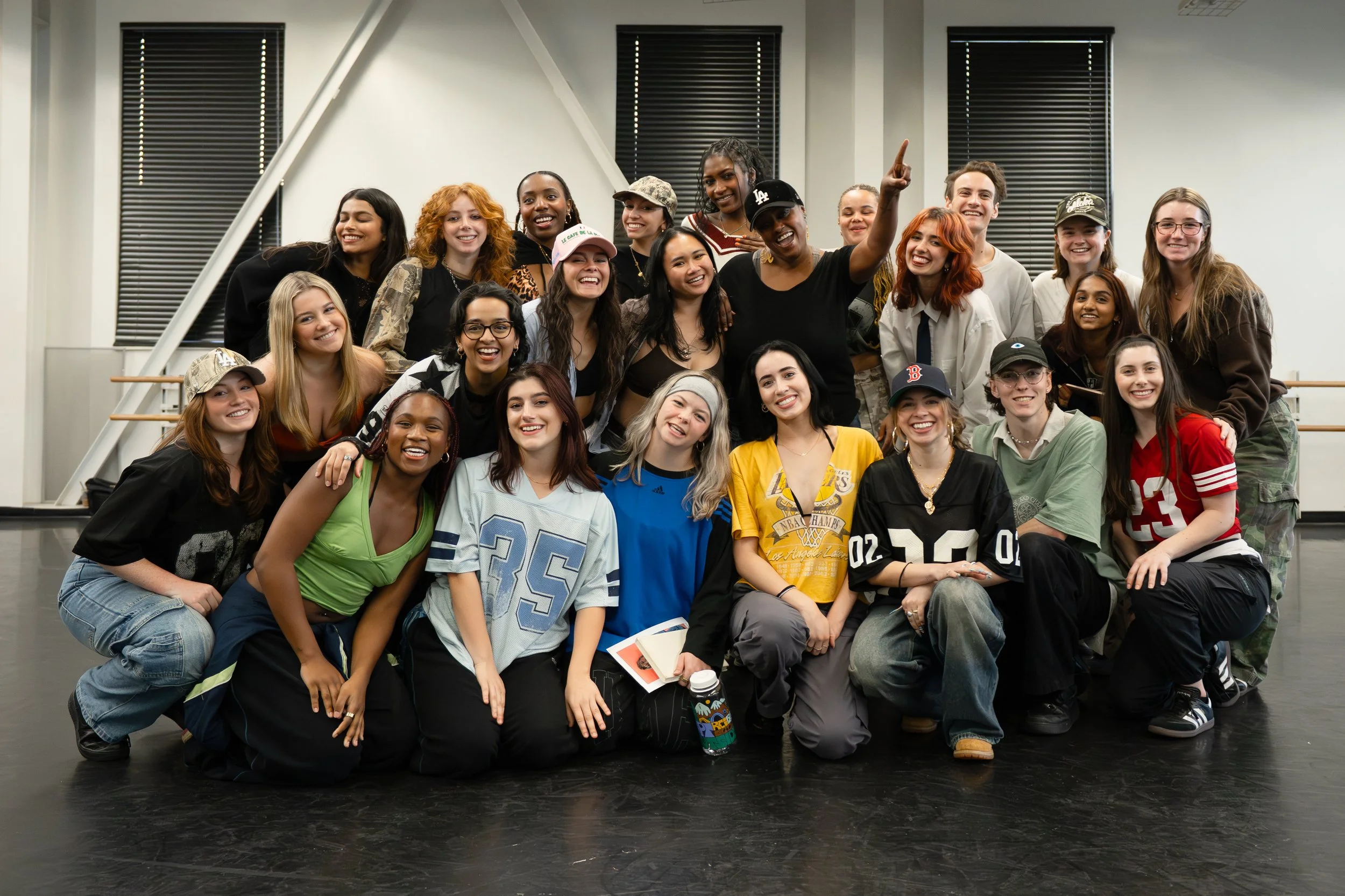 Group of diverse women and girls posing together indoors, smiling and making playful gestures.