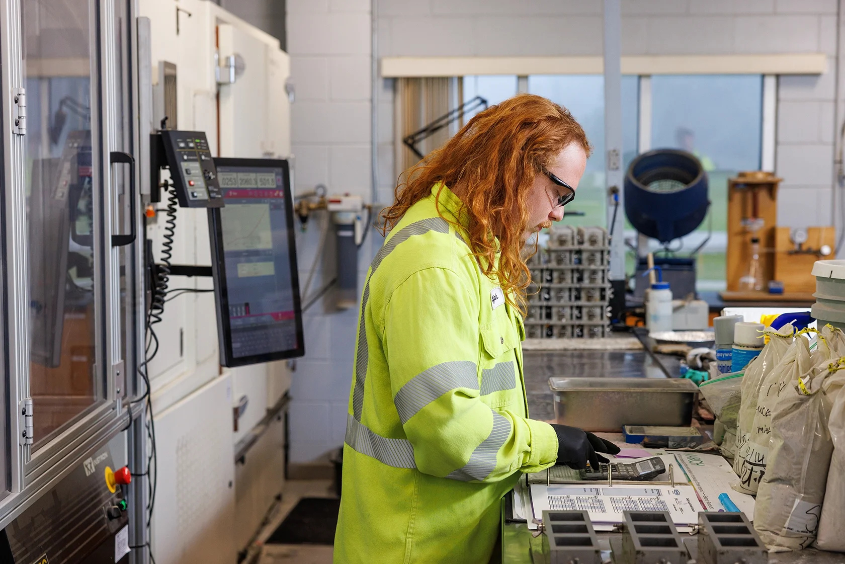Image of a male worker in safety gear inspecting materials for testing