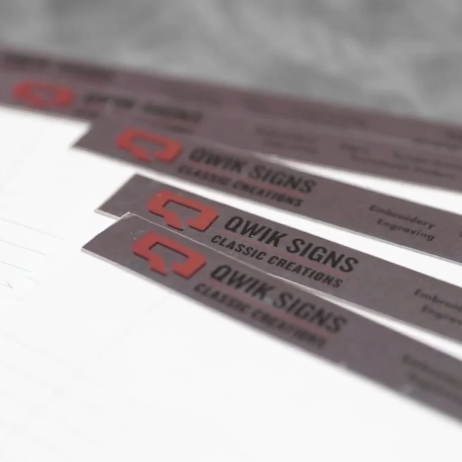 Close-up photo of three custom branded promotional notebooks, reading 'QWIK SIGNS and CLASSIC CREATIONS'.