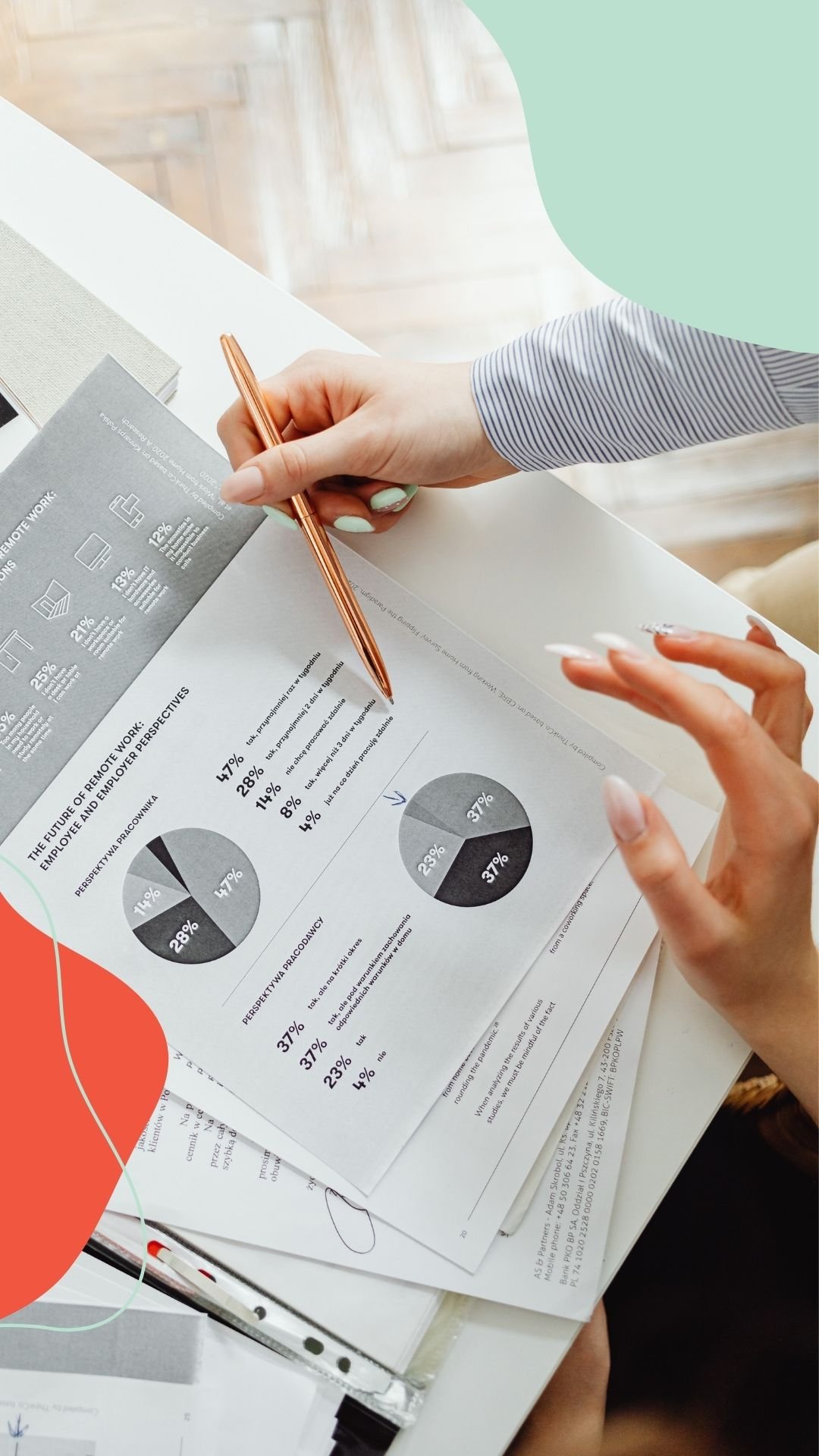 Two people are discussing printed charts and graphs on a desk, with one person holding a pen.