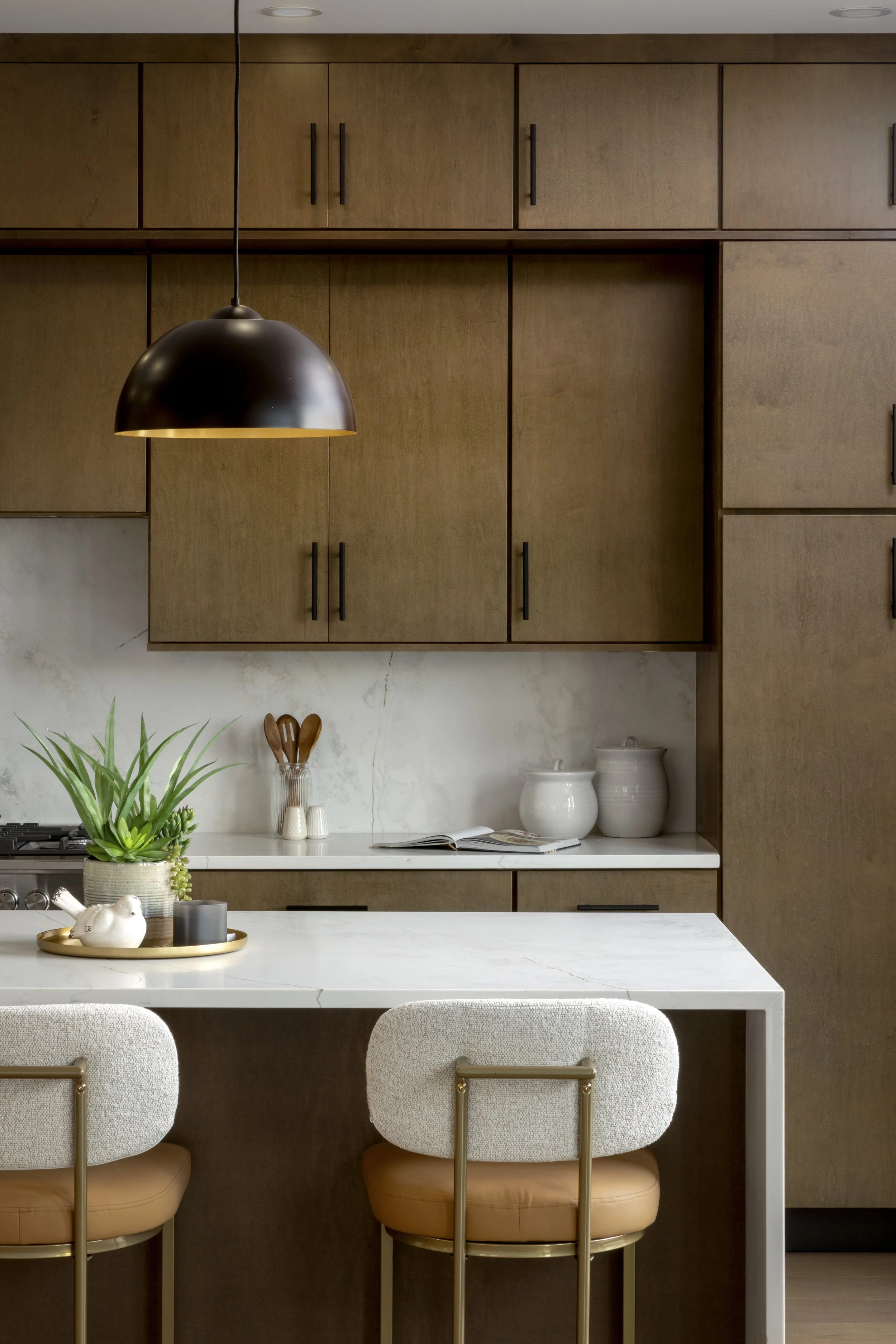 Upgraded Kitchen with double-stack cabinets, waterfall quartz island, solid surface backsplash, and custom pendants.  A designer inspired kitchen.