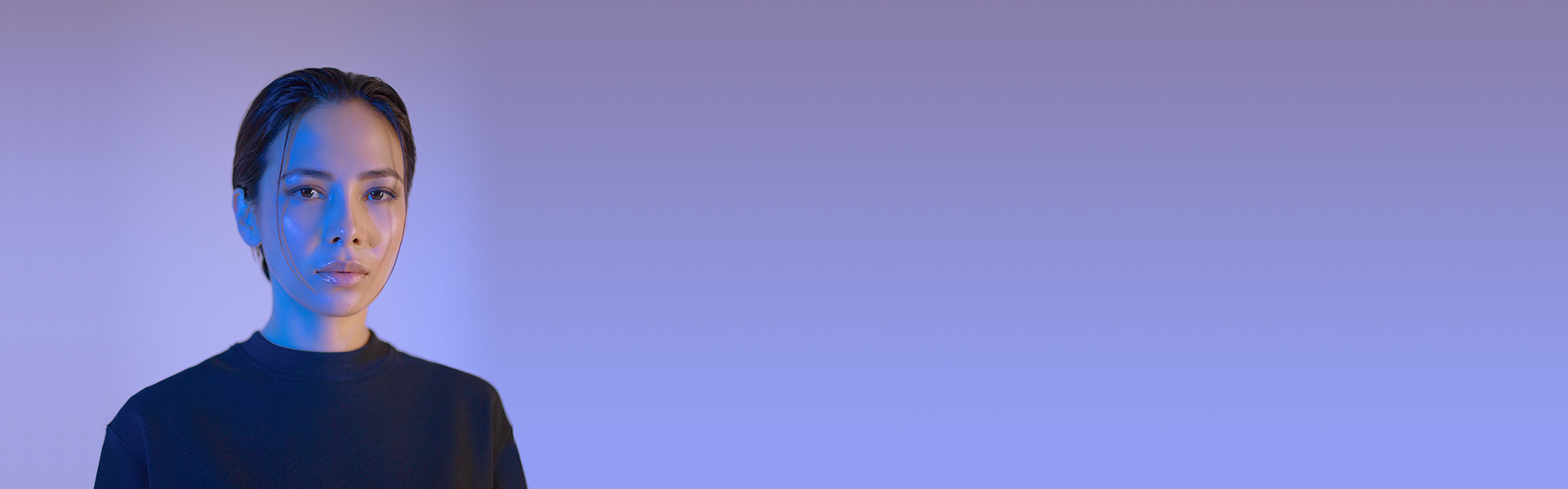 A woman with short dark hair looking at the camera against a blue and purple gradient background.