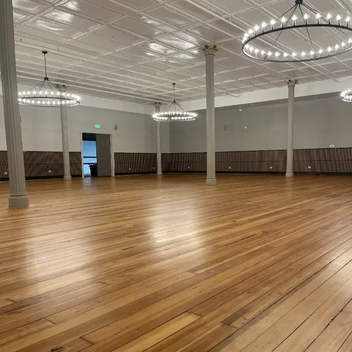 An empty spacious event hall with polished wooden floors.