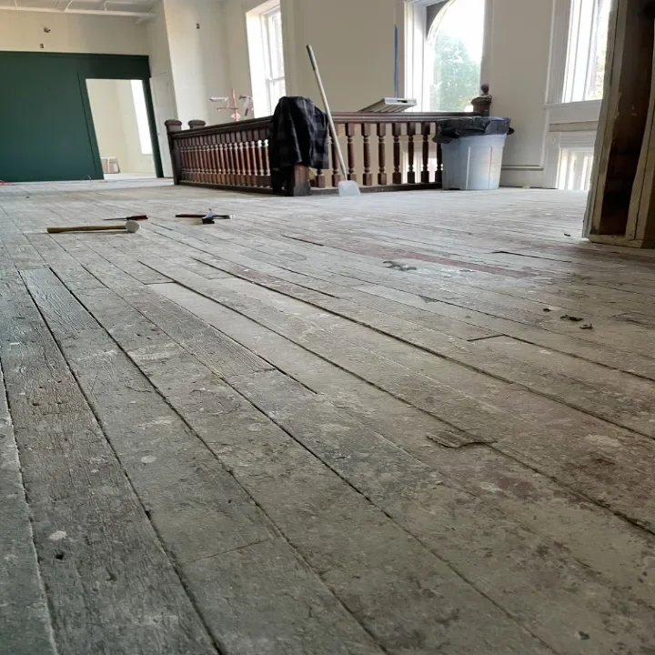 A room under renovation with exposed old wooden floorboards.