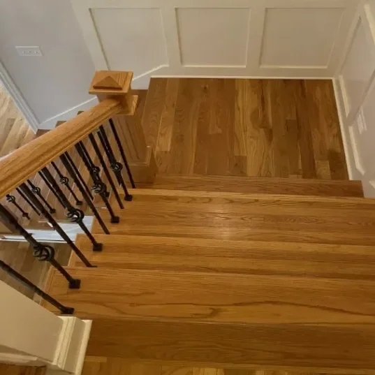 Top view of a wooden staircase with a wooden handrail and iron spindles.