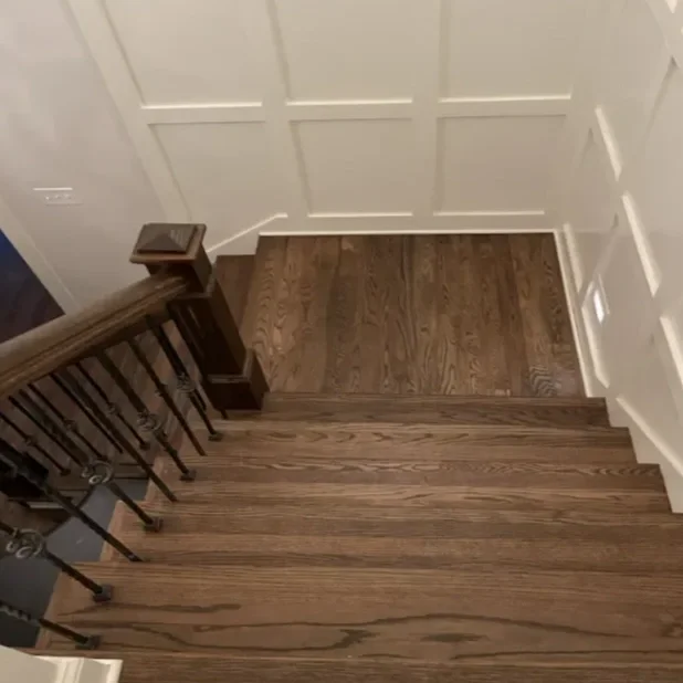 View of a wooden staircase with a dark wood handrail and balusters.
