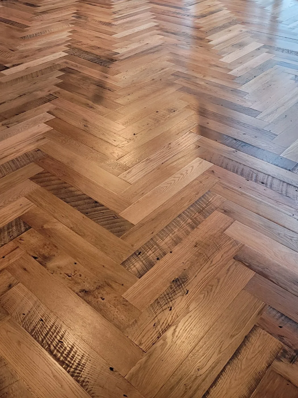 Close-up of a hardwood floor with a herringbone pattern.