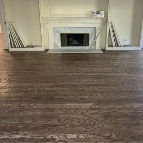 Empty living room with wooden floor and a white fireplace with a marble surround.